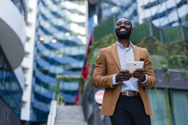 istock Smiling Businessman Holding Tablet Outdoors in Urban Setting 2200428531