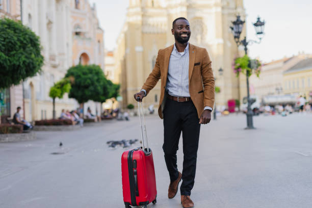 istock Businessman Traveling with Red Suitcase in Urban Setting 2200428739