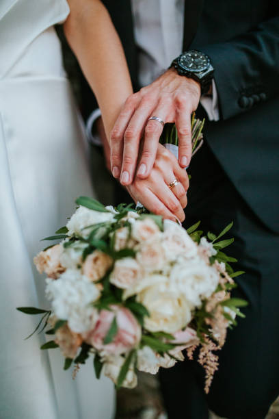 istock Newlyweds' Hands with Wedding Rings and Elegant Bouquet 2200429542