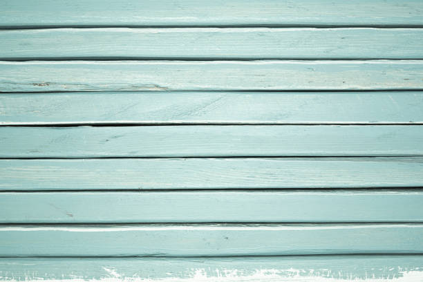 Weathered teal wooden planks showcase rustic texture, providing a serene backdrop. The color and grain add character.