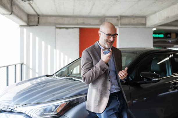 istock Man talking on phone in a parking area beside his car 2200431979