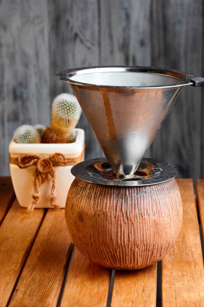 istock Metal pour over drip cone (V60) with rustic vintage handmade clay cup and little cactus in flowerpot on wooden background 2200433626