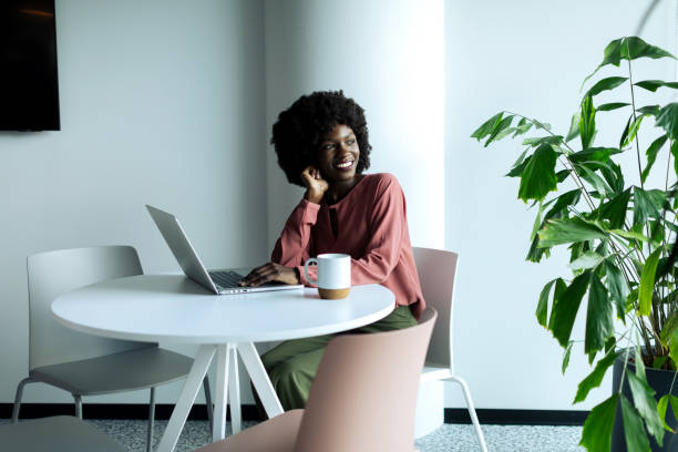 istock Young businesswoman sitting and using laptop while drinking coffee in the modern office 2200436551