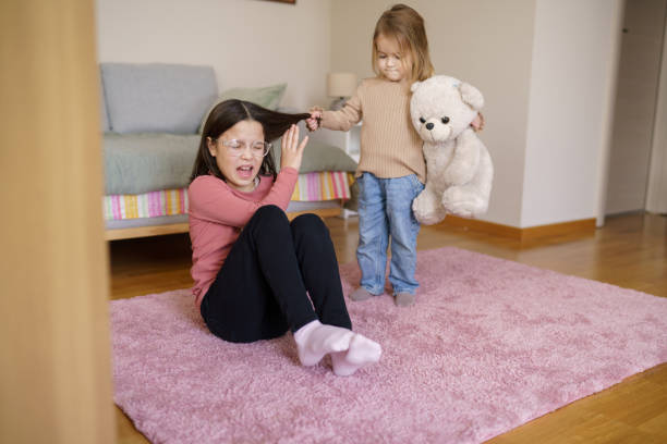 istock A little girl is pulling her older sister's hair 2200437256