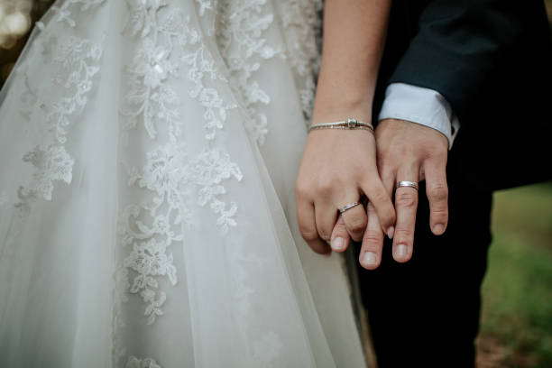 istock Bride and Groom Holding Hands with Wedding Rings 2200437818