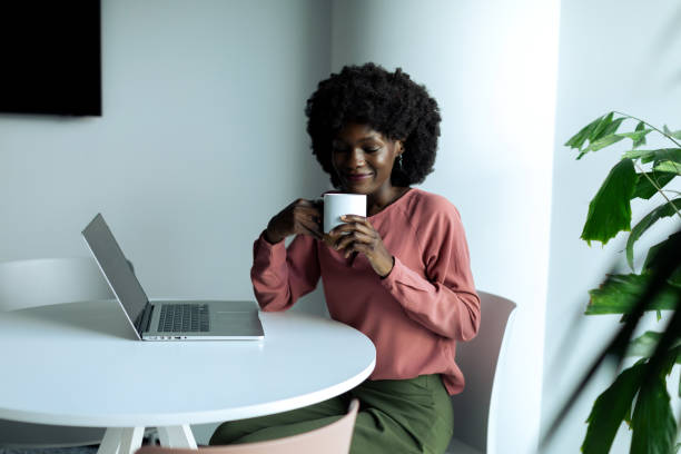 istock Young businesswoman sitting and using laptop while drinking coffee in the modern office 2200437939
