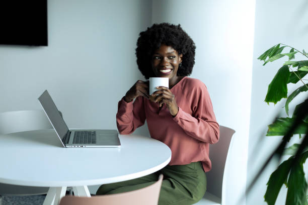 istock Young businesswoman sitting and using laptop while drinking coffee in the modern office 2200438443