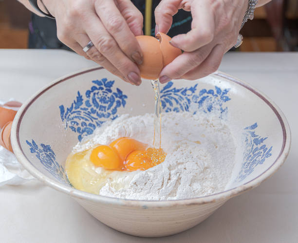 istock Cracking an egg with your hands and pouring it over flour in a ceramic bowl. 2200438955