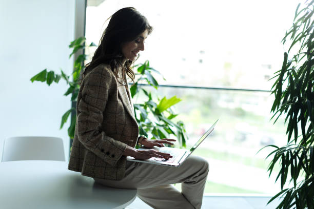 istock Young businesswoman sitting and using laptop while drinking coffee in the modern office 2200441076