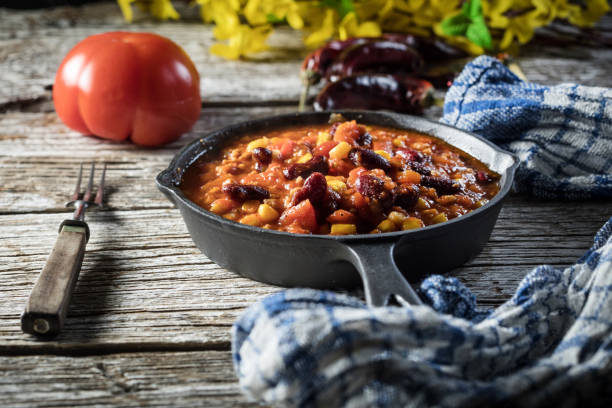 Chili con carne in a frying pan on a wooden background. Selective focus.