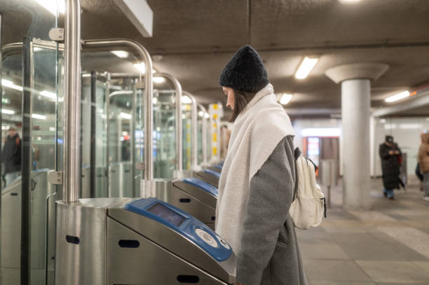 istock Young woman using ticket to enter subway station turnstile 2200448092