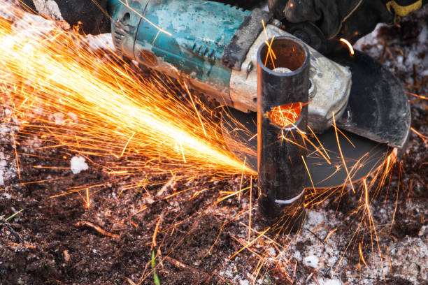 istock Worker Cutting Metal Pipe with Angle Grinder, Creating Sparks Outdoors 2200448570