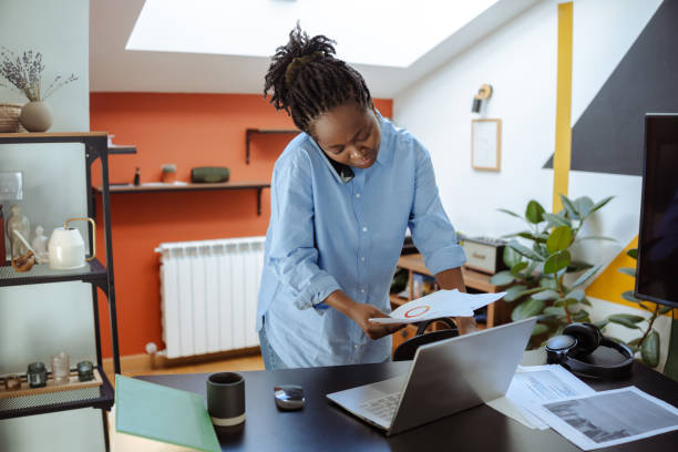 Professional woman multitasking with a laptop and phone in a home office