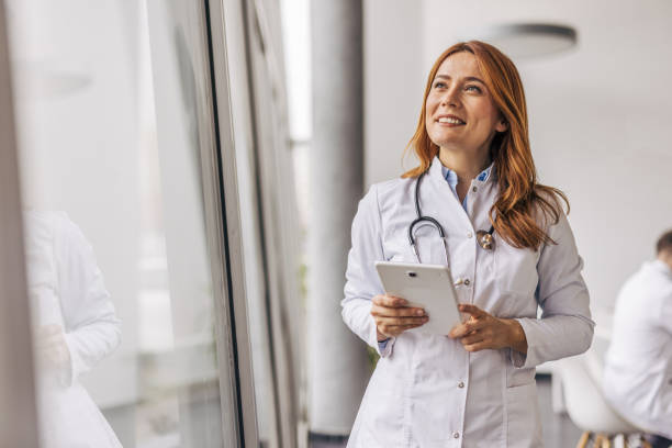 istock Female doctor holding digital tablet and looking up thoughtfully 2200452364
