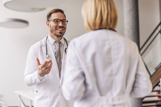 istock Doctors wearing lab coats discussing in hospital hallway 2200453699