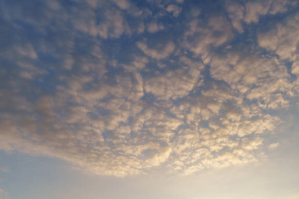 A captivating view of scattered clouds illuminated by a golden hue against a blue sky, evoking a serene and tranquil atmosphere. Perfect for themes of nature, peace, and dreamy landscapes.