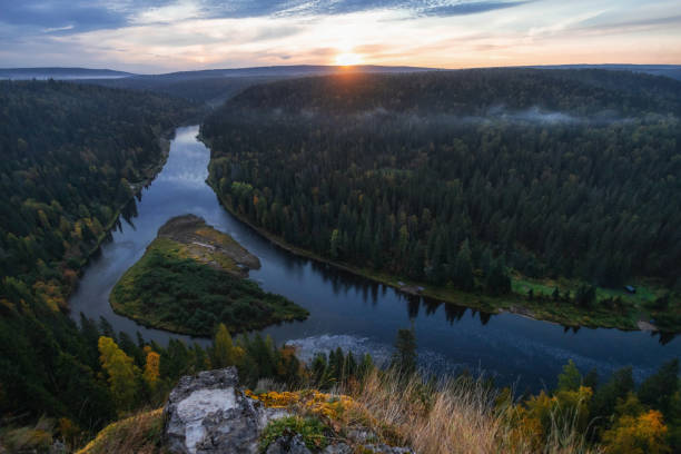 istock A stunning sunset casts golden hues over a winding river nestled between dense forests and hills, showcasing the beauty of untouched nature during twilight hours 2200464360