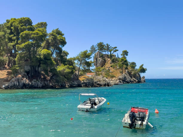 Parga, Greece - July 3, 2024: Motorboats in the azure Ionian Sea with the Saint Prokopios Holy Chapel island rocks and trees behind