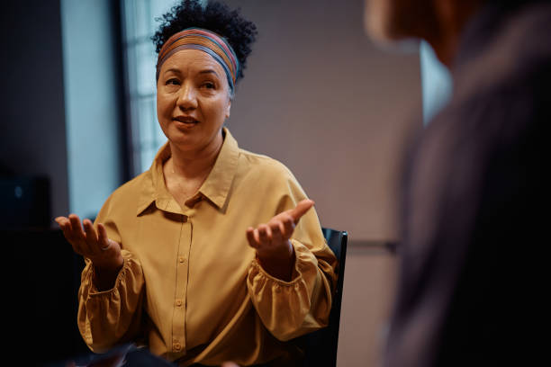 istock Mature woman talking about mental health issues during a group therapy session. 2200467319