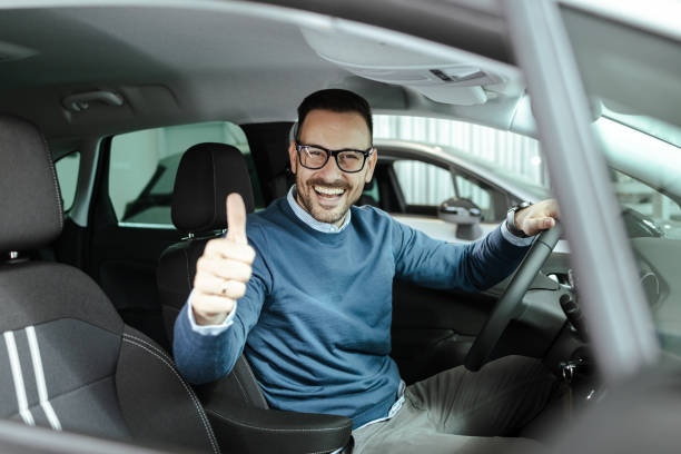 istock Smiling man giving a thumbs up gesture while sitting in a modern car 2200467556