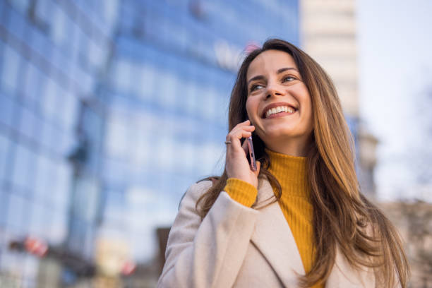 istock woman speaking on her smartphone in a modern cityscape 2200472391