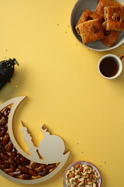 istock Ramadan Kareem concept with traditional sweets, dates, nuts, a cup of tea, and a decorative lantern on a yellow background. Flat lay, top view, vertical. Ideal for festive Islamic cultural themes 2200473596