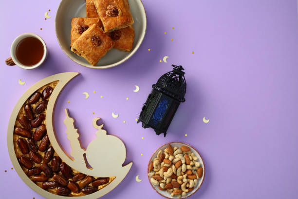 istock Ramadan flat lay with traditional sweets, dates, nuts, tea, and a decorative lantern on a purple background 2200474185