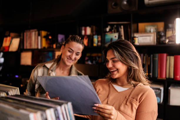 In a vibrant vinyl record store, two women enjoy a relaxed shopping experience, exchanging opinions on album covers and discussing their favorite bands.