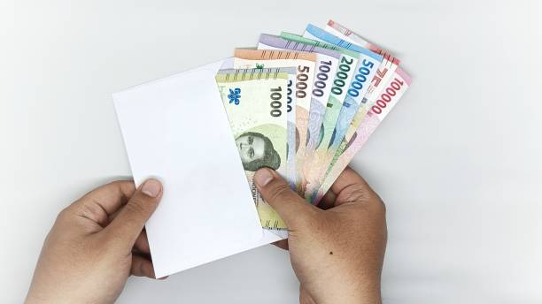 istock two hands take out a collection of Indonesian banknotes from a white envelope. denominations of 1000, 2000, 5000, 10000, 20000, 50000, 75000, 10000 rupiah 2200486403