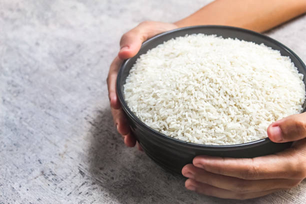 istock hands holding a bowl of raw rice 2200486577