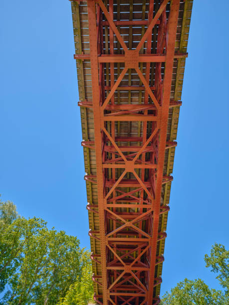 istock Large red iron bridge spanning a peaceful wooded waterway 2200505897