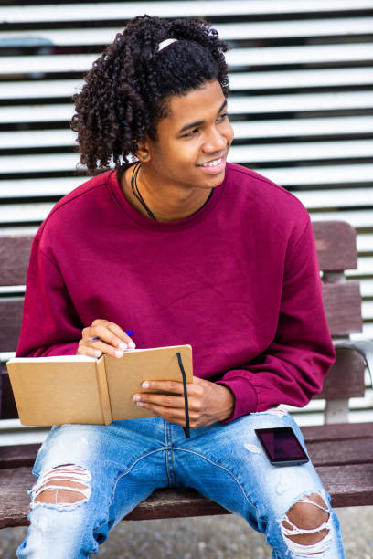 istock Happy man sitting outside with mobile phone and notebook 2200506063