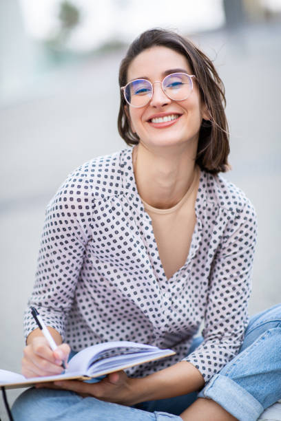 istock Pretty young woman sitting outside with book 2200506526