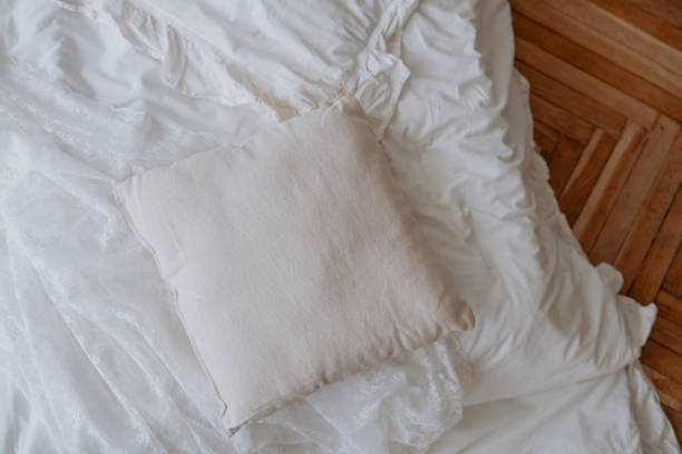 istock Soft beige pillow resting on a crumpled white blanket in a cozy bedroom 2200506603