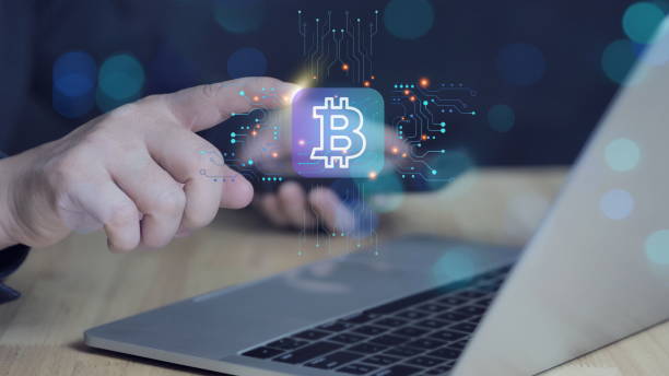istock usinessman using computer with Crypto Currency icon in his hand. Male hand holding futuristic BTC chip in the center and circuit board with vibrant data transfers. 2200513341