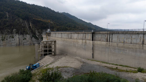 istock Concrete dam holding back water reservoir with construction crane in Mignano, PC Italy 2200514585