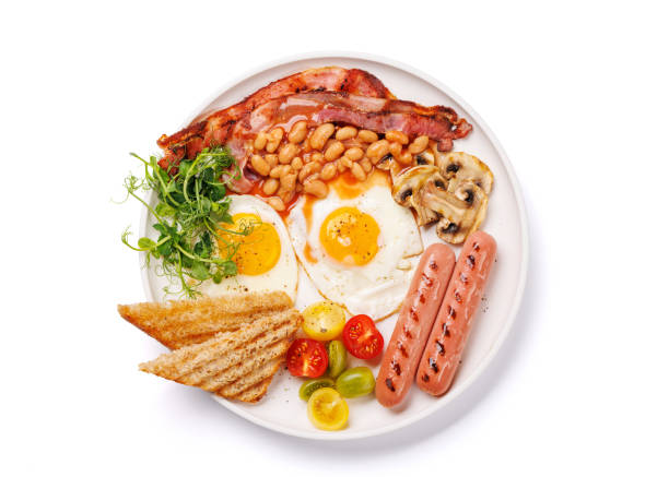 istock A classic breakfast plate featuring sunny-side-up eggs, crispy bacon, sausages, and fresh tomatoes 2200520591