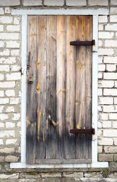 A wooden door with a rusty lock. The door is old and has a weathered appearance. The door is located in front of a brick wall