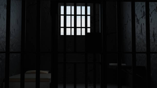 istock 3D model of a solitary prison cell behind bars with a bed and a table and a window with light 2200529980