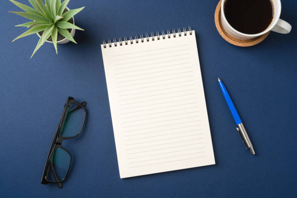 istock Top view of a workspace with a blank notebook, pen, glasses, coffee, and plant 2200530382