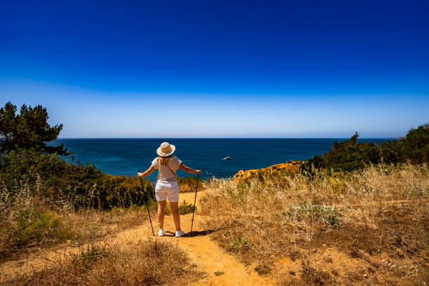 istock Mature woman practicing Nordic walking on path on cliffs during sightseeing Ponta da Piedade on beautiful sunny day 2200533201