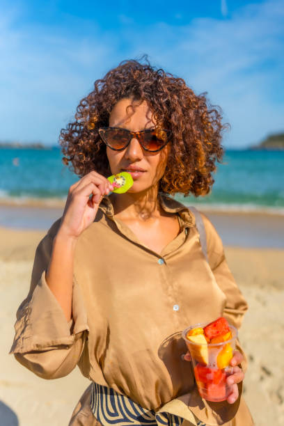 istock Woman refreshing with tropical fruit on the beach 2200536716