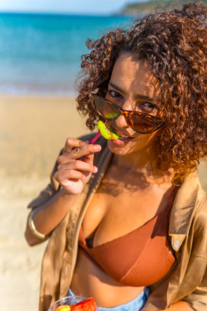istock Sensual woman in bikini biting tropical fruit at beach 2200536829