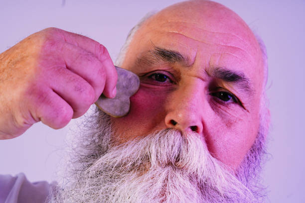 Senior old man with gray beard beauty portrait in studio - Stylish older male adult doing skin care treatment, concepts about elderly and lifestyle