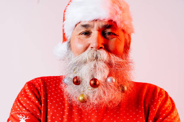 Senior old man with gray beard with Santa Claus portrait in studio - Funny stylish older male adult with cool style, concepts about elderly, lifestyle and Christmas