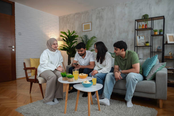 Four Young Adults Using Smartphone and Relaxing on Sofa at Home