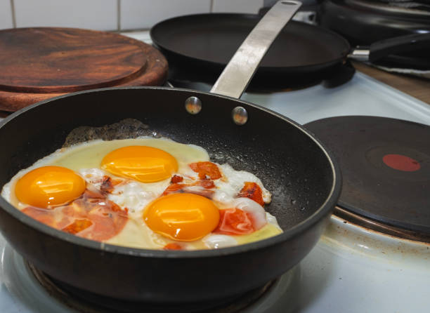 istock Fried eggs with tomatoes are cooked in a frying pan, electric stove. 2200541405