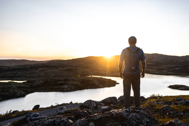 istock Hiker Standing on Rocks Overlooking Scenic Lake at Sunset 2200542863