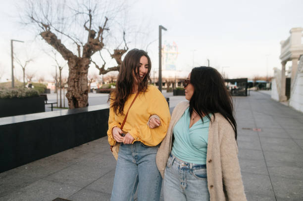istock Two cheerful women walking arm in arm 2200543345