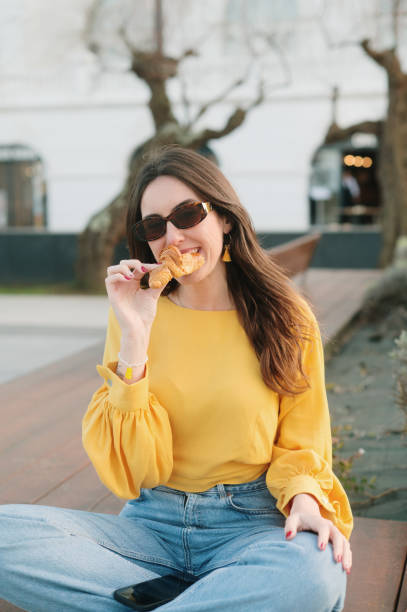 istock Young woman eating a croissant 2200543435